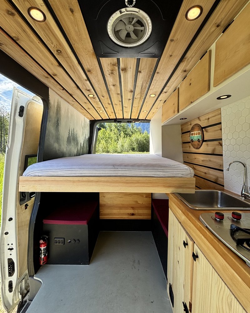 Interior of a TryVanLife campervan with bed and kitchen setup for rental in Whistler